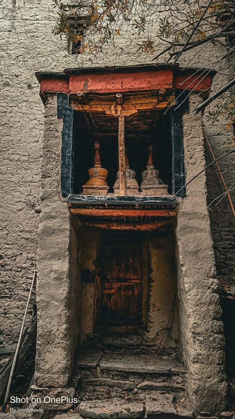 The old doorway of the 200-year-old house, beneath a window of three chortens